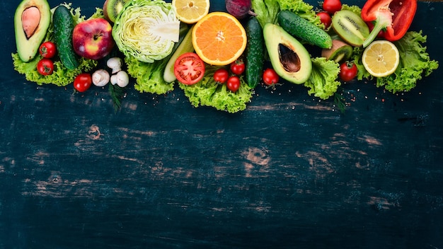 Gesundes Essen Gemüse und Obst auf einem schwarzen Hintergrund aus Holz Draufsicht Kopieren Sie Platz