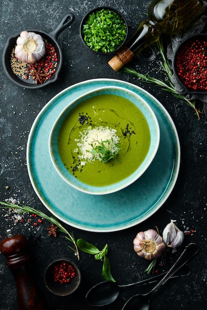 Gesundes Essen Grüne Suppe mit Brokkoli und Spinat in einem Teller auf schwarzem Steinhintergrund Draufsicht Rustikaler Stil