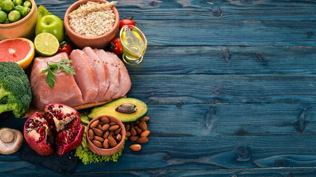 Gesundes Essen Rohes Fleisch Avocado Brokkoli frisches Gemüse Nüsse und Früchte Auf einem hölzernen Hintergrund Ansicht von oben Kopieren Sie Platz