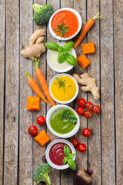 Foto gesundes essen, sauberes essenskonzept. vielzahl von bunten saisonalen herbstgemüse cremige suppen mit zutaten. kürbis, brokkoli, karotte, rote beete, kartoffel, tomatenspinat. flach legen