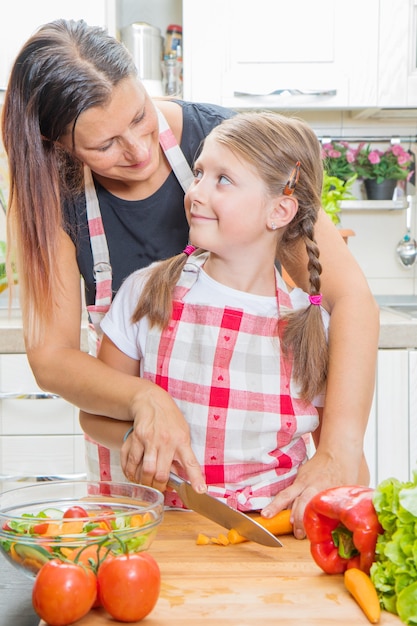 Gesundes Essen zu Hause. Glückliche Familie in der Küche. Mutter und Kindertochter bereiten das Gemüse vor