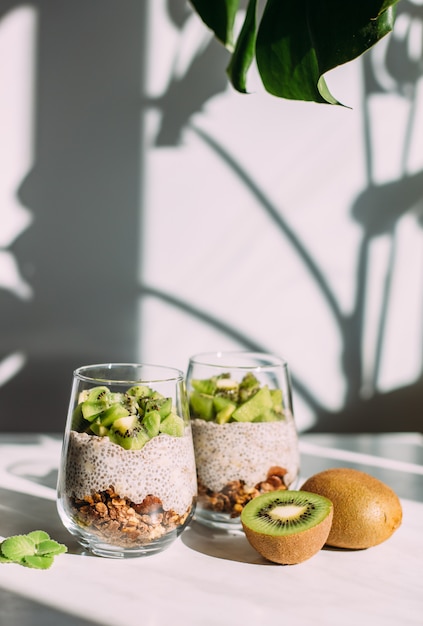 Gesundes Frühstück. Chia-Pudding mit Kiwi und Müsli im Glas auf weißem Hintergrund