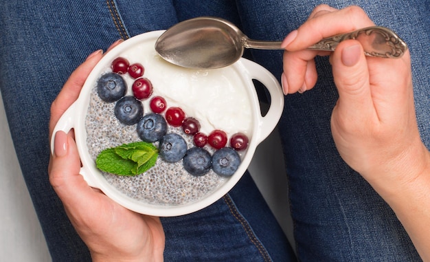 Gesundes Frühstück Chia-Samen und Joghurt mit Beeren in Frauenhänden