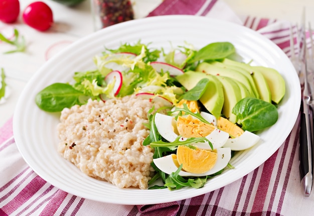 Gesundes Frühstück. Diät-Menü. Haferbrei und Avocado Salat und Eier.