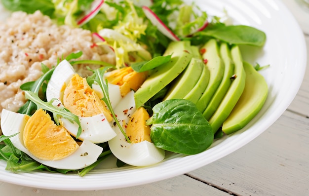 Gesundes Frühstück. Diätmenü. Haferbrei und Avocadosalat und Eier.