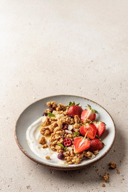 Foto gesundes frühstück, frisches müsli-müsli mit joghurt, erdbeere und honig auf beige