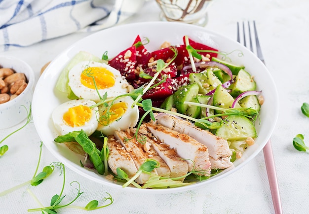 Gesundes Frühstück. Gekochter Eiersalat mit Gemüse, Gurken, roter Beete und gegrilltem Hähnchenfilet und roten Zwiebeln. Mittagessen.