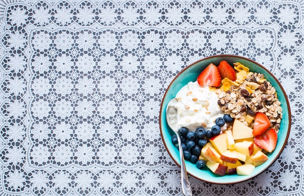 Gesundes Frühstück, Getreide mit Joghurt, Erdbeeren, Blaubeere, Apfel, Banane auf Holz