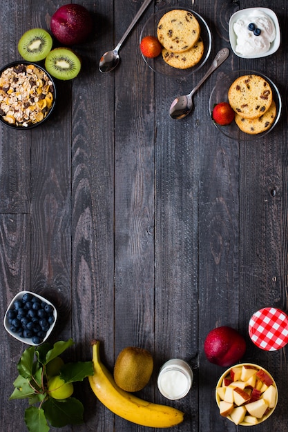 Gesundes Frühstück, Getreide mit Jogurt, Erdbeeren, Blaubeere, Apfel, Banane, auf rustikaler hölzerner, Draufsicht