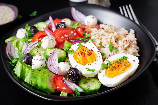 Gesundes Frühstück Griechisch inspirierte Haferflocken mit frischen Gurken, Tomaten, Oliven, Salat, Mozzarella-Käse und gekochtem Ei Draufsicht