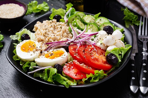 Gesundes Frühstück Herzhafte Haferflocken mit frischen Gurken, Tomaten, Oliven, Salat, Mozzarella-Käse und gekochtem Ei Draufsicht