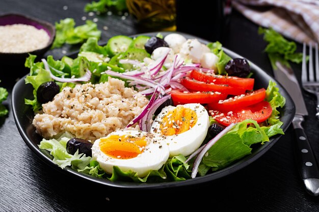 Gesundes Frühstück Herzhafte Haferflocken mit frischen Gurken, Tomaten, Oliven, Salat, Mozzarella-Käse und gekochtem Ei Draufsicht