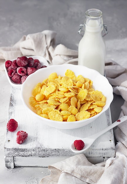 Gesundes Frühstück mit Cornflakes und Milch in einer Schüssel mit Himbeeren.