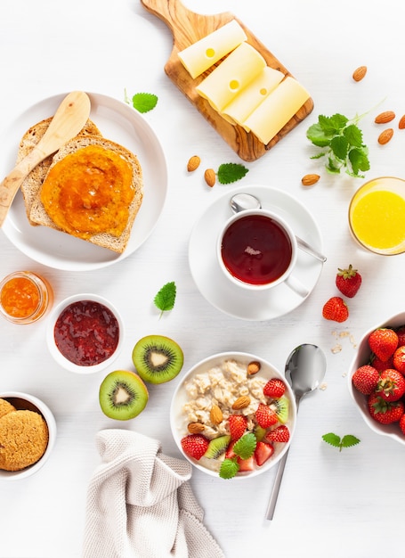 Gesundes Frühstück mit Haferbrei, Erdbeere, Nüssen, Toast, Marmelade und Tee. Draufsicht
