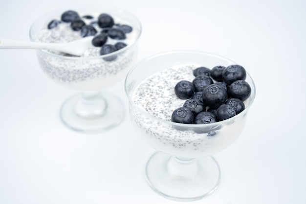 Gesundes Frühstück mit Joghurt, Chiasamen und Blaubeerglasbechern auf weißem Hintergrund