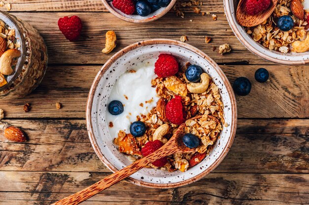 Gesundes Frühstück mit Joghurt und gebackenem Müsli mit Beeren in zwei kleinen Schalen Müsli gebacken mit Nüssen, Kokosöl und Honig