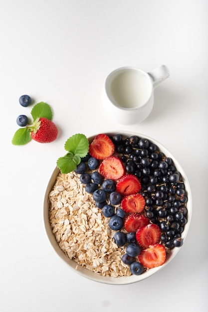 Gesundes Frühstück, Müsli mit Johannisbeeren, Blaubeeren und Erdbeeren, serviert in Brüllen auf hellem Raum