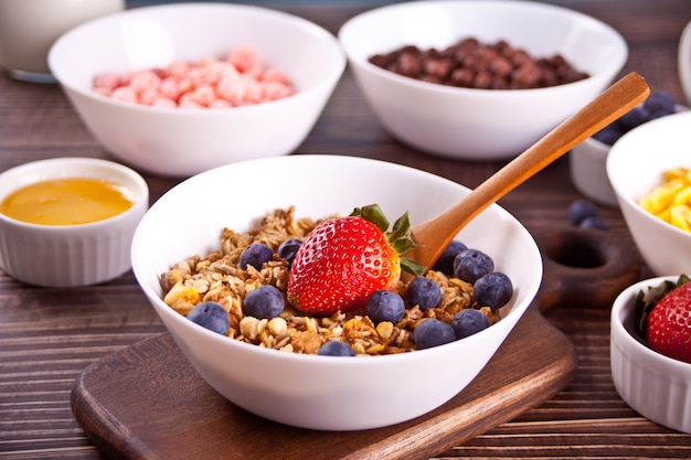 Gesundes frühstück. müsli, müsli mit frischen beeren und anderen flocken und maisbällchen im hintergrund.