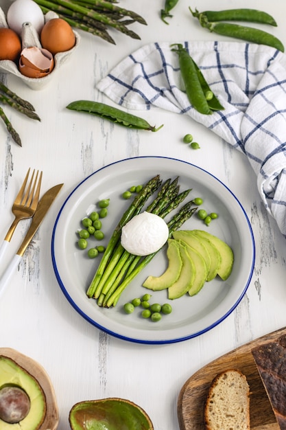 Gesundes frühstück - pochierte eier mit spargel, avocado und grünen erbsen