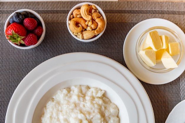 Gesundes Frühstück. Reisbreischüssel mit Beeren und Nüssen auf dem Tisch, heißes und gesundes Frühstück, Draufsicht