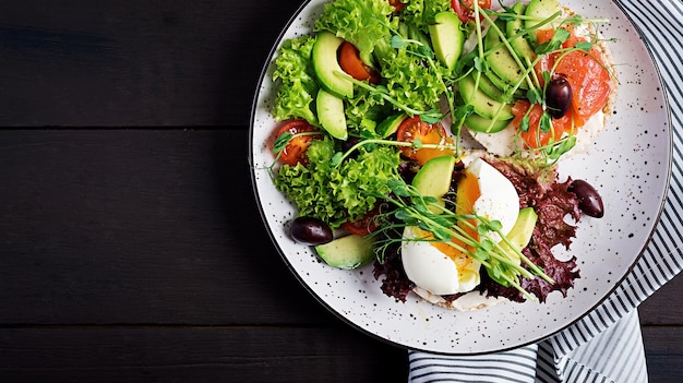 Gesundes Frühstück Sandwiches mit Sahne, Käse, Avocado, gekochtem Ei und geräuchertem Lachs auf dem Teller