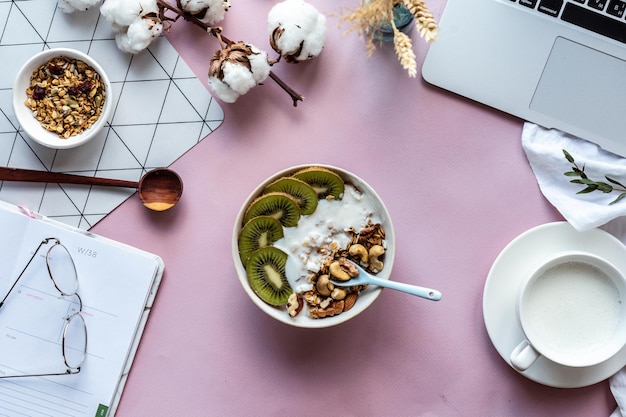 Gesundes Frühstück Schüssel Milch Laptop-Organizer auf rosa Tischhintergrundkonzept