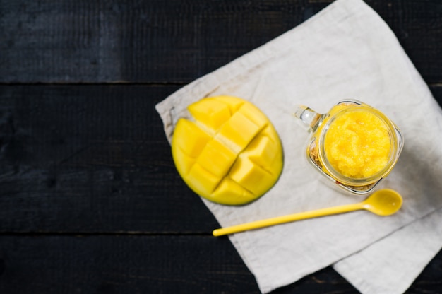 Gesundes Frühstücks-Müsli und Joghurt mit Mango-Smoothie in Einweckgläsern.