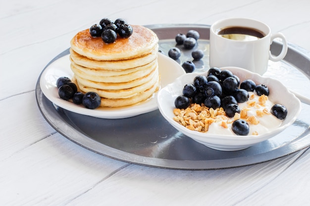 Gesundes Frühstücksmüsli mit Joghurt und Pfannkuchen mit Blaubeeren