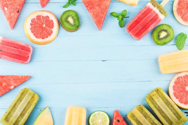 Gesundes ganzes Frucht-Eis am Stiel mit Beeren-Kiwi-Wassermelonen-Kantalupe auf hölzernem Weinlese-Tisch