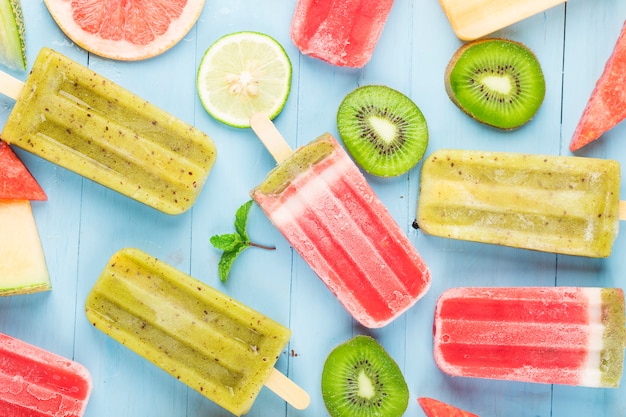 Gesundes ganzes Frucht-Eis am Stiel mit Beeren-Kiwi-Wassermelonen-Kantalupe auf hölzernem Weinlese-Tisch