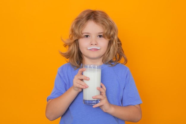 Gesundes Getränk mit Kalzium und Protein für Kinder Kleiner Junge trinkt ein Glas Milch mit lustigen Emotionen auf gelbem Hintergrund Kind trinkt Milch Studioportrait Nettes Kind hält ein Glas Milch