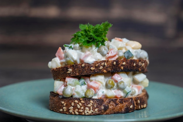 Gesundes hausgemachtes Doppelsandwich mit Olivier-Salat im Teller bereit, ukrainisches Essen zu essen