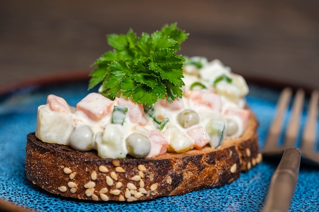 Gesundes hausgemachtes Sandwich mit Oliviersalat im Teller, essfertig, Nahaufnahme. Ukrainisches Essen