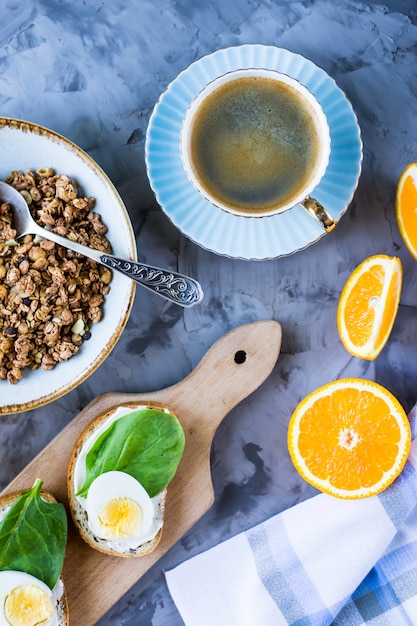 Gesundes herzhaftes Frühstück - Müsli, Sandwich mit Ei, Kaffee, Orange und Saft