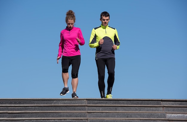 Gesundes junges Paar, das am frühen Morgen auf Stufen joggt