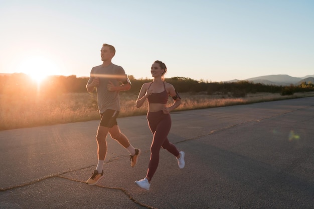 Gesundes junges Paar, das am frühen Morgen in den Straßen der Stadt mit einem wunderschönen Sonnenaufgang im Hintergrund joggt. Foto in hoher Qualität