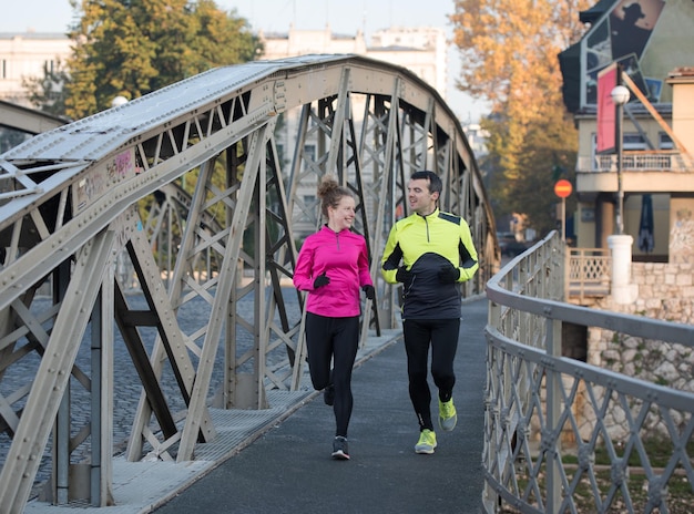 Gesundes junges Paar Joggen in der Stadt am frühen Morgen mit Sonnenaufgang im Hintergrund