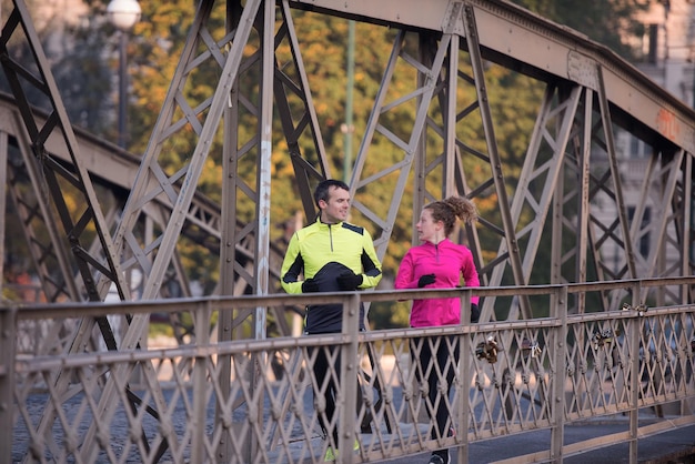 Gesundes junges Paar Joggen in der Stadt am frühen Morgen mit Sonnenaufgang im Hintergrund