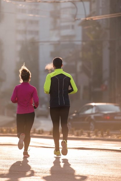 Gesundes junges Paar Joggen in der Stadt am frühen Morgen mit Sonnenaufgang im Hintergrund