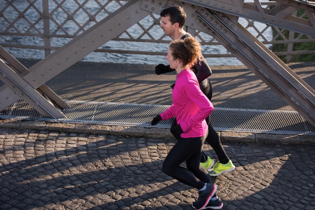 Gesundes junges Paar Joggen in der Stadt am frühen Morgen mit Sonnenaufgang im Hintergrund