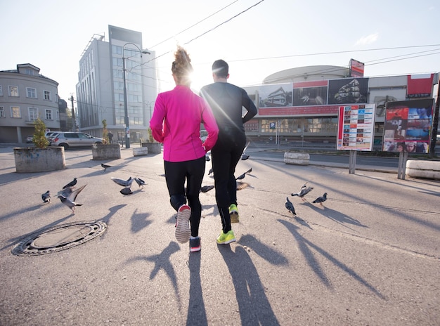 Gesundes junges Paar Joggen in der Stadt am frühen Morgen mit Sonnenaufgang im Hintergrund