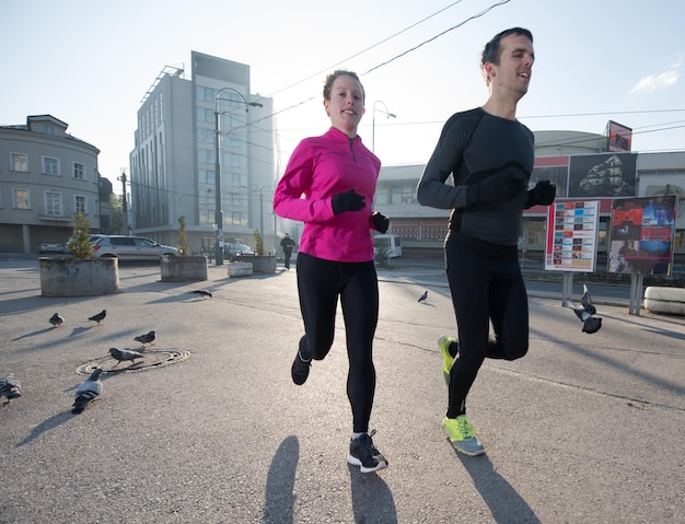 Gesundes junges Paar Joggen in der Stadt am frühen Morgen mit Sonnenaufgang im Hintergrund