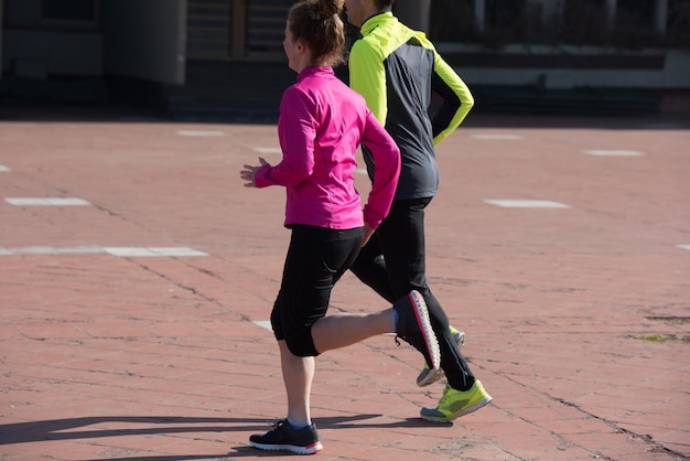 Gesundes junges Paar Joggen in der Stadt am frühen Morgen mit Sonnenaufgang im Hintergrund