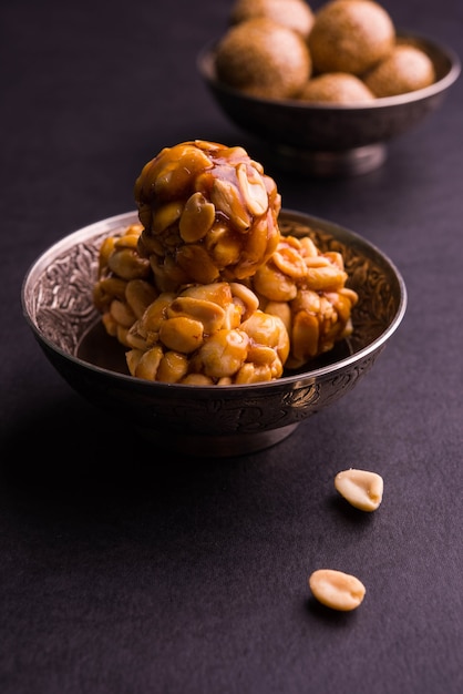 Gesundes Laddoo mit gerösteten Erdnüssen, Sesam und geteiltem Daliya mit Jaggery, serviert in einer Holzplatte, selektiver Fokus