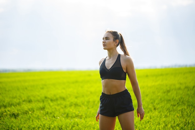 Gesundes Lebensstilkonzept. Junge attraktive Frau in Sportkleidung macht ihre Hand vor dem Training in der Natur im Morgengrauen strecken. Muskelerwärmung