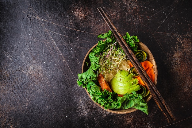 Gesundes Mittagessen des strengen Vegetariers in der Kokosnussschüssel. Buddha-Schüssel auf einem dunklen Hintergrund.