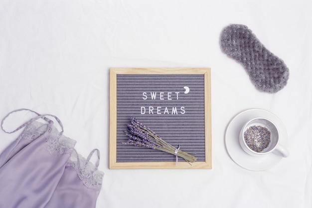 Gesundes Nachtschlafkonzept Tasse Lavendel Tee Seidenpyjama Schlafmaske Aromen für besseres Einschlafen