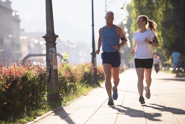 Gesundes reifes Paar Joggen in der Stadt am frühen Morgen mit Sonnenaufgang im Hintergrund