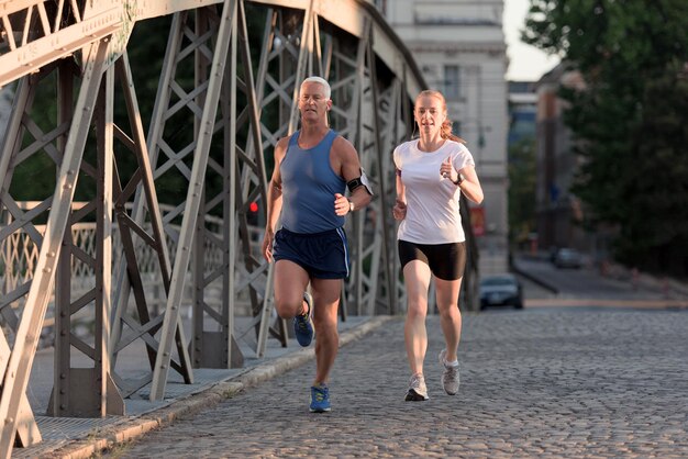 Gesundes reifes Paar Joggen in der Stadt am frühen Morgen mit Sonnenaufgang im Hintergrund