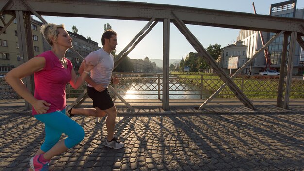 Gesundes reifes Paar Joggen in der Stadt am frühen Morgen mit Sonnenaufgang im Hintergrund